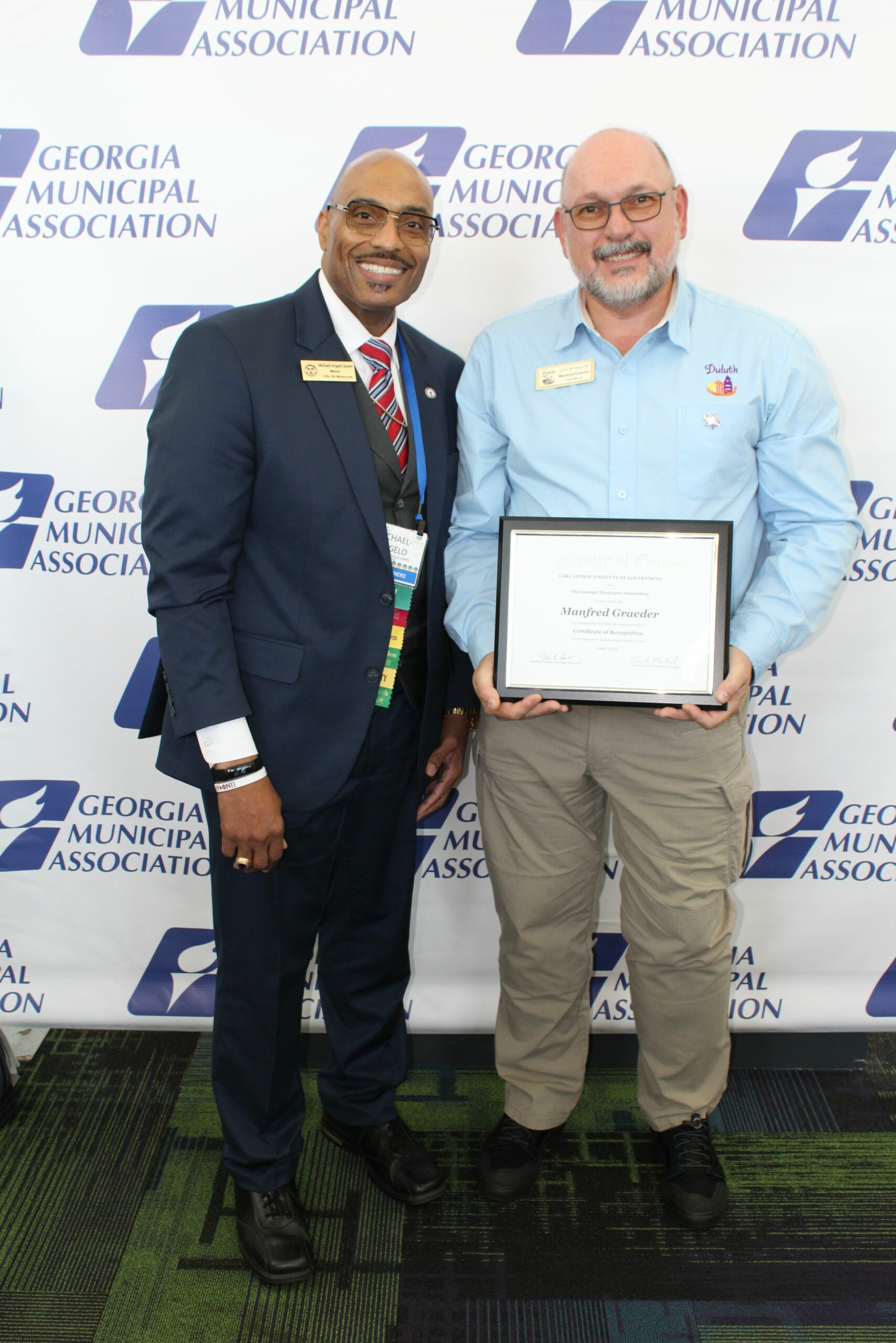 Michael-Angelo James, Mayor of the City of Waycross (Left) and Council Member Manfred Graeder from the City of Duluth (Right) holding his award.